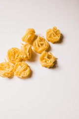 uncooked rolled tagliatelle pasta on white background