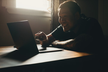  A asian man working  on laptop in dark area. Pointing to the screen. Happy gesture.