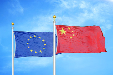 European Union and China two flags on flagpoles and blue cloudy sky
