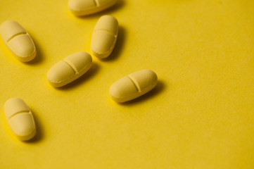 Medical pills or vitamins on a yellow background macro closeup. There is a place to insert text, copy space