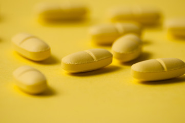 Medical pills or vitamins on a yellow background macro closeup