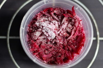 Frosty grated beetroot in bowl on black baclground