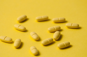 Medical pills or vitamins on a yellow background macro closeup. There is a place to insert text, copy space
