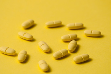 Fototapeta na wymiar Medical pills or vitamins on a yellow background macro closeup. There is a place to insert text, copy space