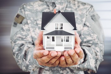 Soldier man holding a model of the house