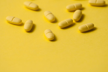 Medical pills or vitamins on a yellow background macro closeup. There is a place to insert text, copy space