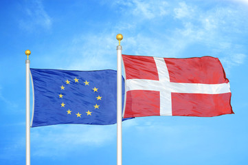 European Union and Denmark two flags on flagpoles and blue cloudy sky
