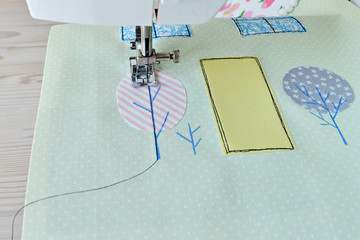 Sewing process: pieces of fabric, applique, needle and thread
