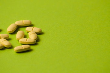 Many yellow pills on a green background with room for copy space