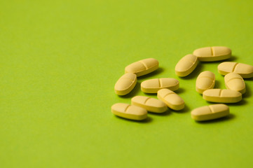 Many yellow pills on a green background with room for copy space