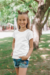 portrait of a little happy girl in a white T-shirt in park