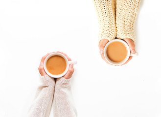 Female hands holding cups of coffee on white table background