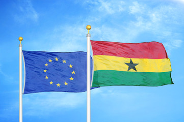 European Union and Ghana two flags on flagpoles and blue cloudy sky