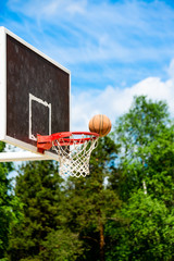 Basketball hoop in the park with green trees as background