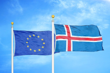 European Union and Iceland two flags on flagpoles and blue cloudy sky © Aleks Taurus