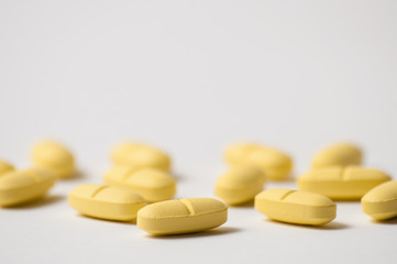 Pills, antibiotics or vitamins of yellow color on a white background macro, close up, place to insert text