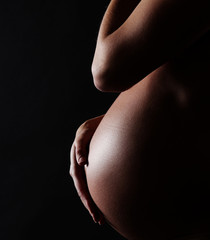 stomach of a pregnant woman on black background with copy space