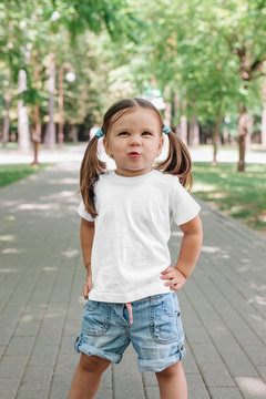 smiling little girl in blank white t-shirt standing in park