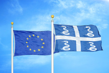 European Union and Martinique snake two flags on flagpoles and blue cloudy sky
