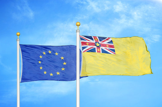 European Union and Niue two flags on flagpoles and blue cloudy sky