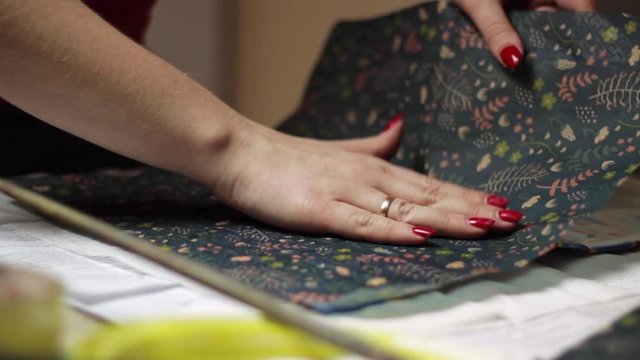 Static view of a woman sticking a patterned sheet to the album of a book to make a decoupage cover
