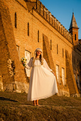 Obraz premium blonde girl in a white dress on nature near architectural monuments in the open air