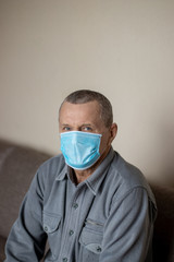 Old man wearing medical mask during COVID-19 coronavirus pandemia, in self isolation, virus epidemy, pneumonia and cough concept