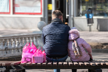 Dad and daughter sit in the park after going to the store. support. lean on a friend's shoulder