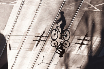 shadow of a cyclist on a road with tram rails. a man rides a bicycle in the city center in the evening.
