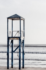 Old blue wooden bay watch observation tower at the beach.