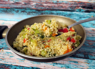 Boiled bulgur with vegetables in a tablespoon in a pan