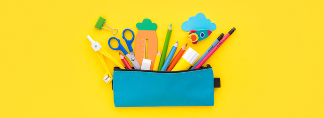 Pencil case and school supplies inside on yellow background. Back to school creative flat lay.   