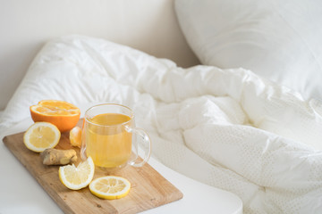 Cup with antipyretic drugs for colds,flu.Tea with citrus vitamin C,ginger root,lemon,orange.Wooden tray in patient's bed. Home self-treatment.Medical quarantine antiviral covid-19 coronavirus therapy