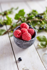 raspberries in a stone bowl on a wooden surface
