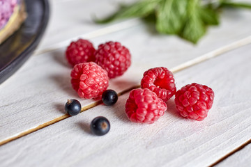 raspberies and blackcurant berries on a wooden surface