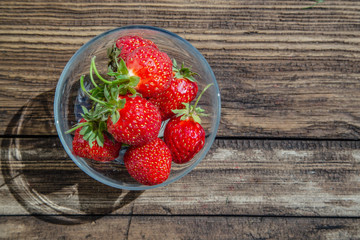 Large strawberries in a glass bowl on a wooden table