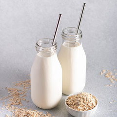 Non dairy oat milk in glass jars with reusable metal straws. Healthy vegan milk alternative still life, copy space. Substitute for traditional cow milk with oat flakes, healthy lifestyle concept