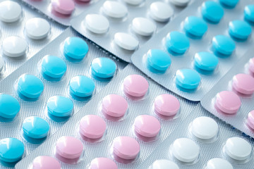 Texture of colorful tablets in blisters, heap of pills. Treatment concept from illness. Medications close-up, round antibiotics.