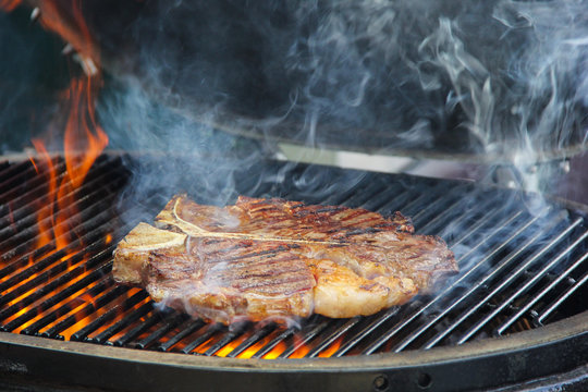 Beef fried on a grill with fire. Meat on the fire with smoke. Picnic. Preparation. Background image, copy space