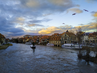 Ships and ferries on the river bank with beautiful European houses, a thunderous blue-orange sky...