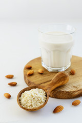 Almond flour in a wooden spoon with a glass of almond milk.