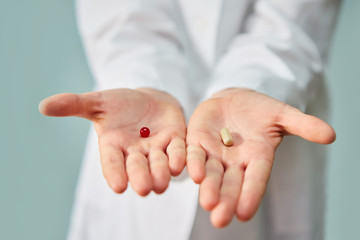 Two different tablets or vitamins in the hands of the doctor, a choice of options.