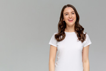 Obraz premium Ciesz się pełnią życia. Portret atrakcyjnej beztroskiej europejskiej kobiety o rudych włosach, bawiącej się pasmami i śmiejącej się głośno na szarym tle, przechylającej głowę, bawiącej się i rozbawionej