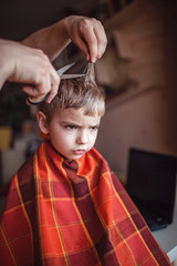 Fototapeta premium Middle aged father cutting hair to his little son by himself at home, life during lockdown