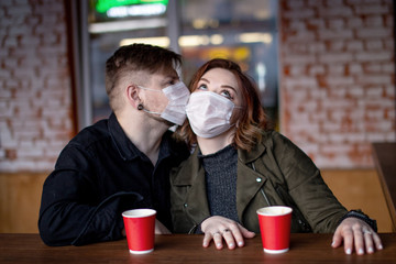 Young beautiful couple of boyfriend and girlfriend lovers are sitting in a cafe in honey masks and kissing during quarantine.