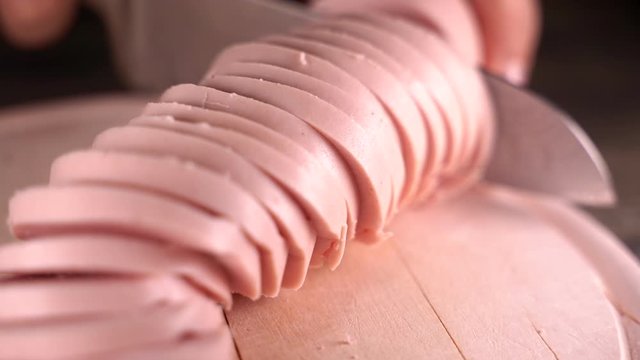 Fleischwurst auf einem Schneidebrett in Scheiben schneiden