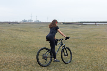 Girl on a mountain bike on offroad, beautiful portrait of a cyclist in rainy weather, Fitness girl rides a modern carbon fiber mountain bike in sportswear. Close-up portrait of a girl in red bandana.