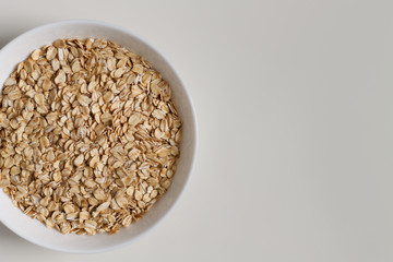 close-up of raw oatmeal on a white plate on a light background. vegetarian food.