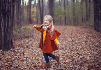 Portrait of happy little girl running in autumn wood