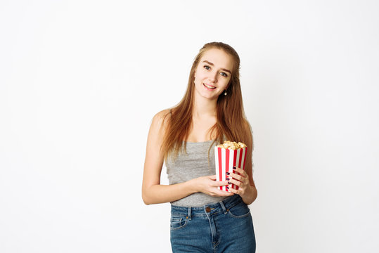 Beautiful blonde girl eat popcorn and watch comedia movie isolated on white background. Copy Space, template for blog and advertising. Woman hold pop corn and watch in camera